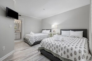 Una habitación de hotel con dos camas, televisión, una mesita y un espejo.