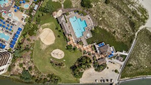 An aerial view of a resort with multiple swimming pools, sun loungers, and a bridge connecting different areas. - Family-Friendly 2BR Condo Near Beach & Barefoot Landing (Myrtle Beach)