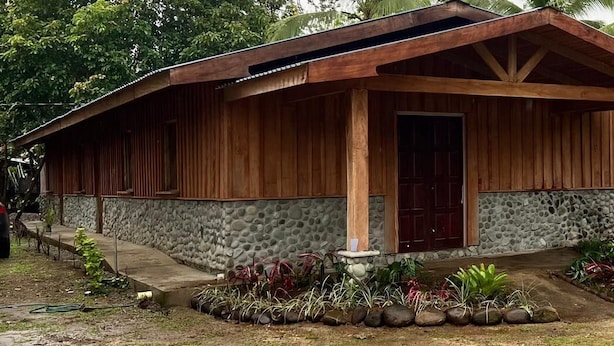 A wooden building with a stone foundation, a porch, and a door.