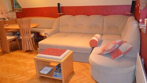 A cozy living room with a sofa, a small table, and a dining area with chairs.