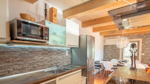 Una cocina moderna con protector mural de piedra, electrodomésticos de acero inoxidable y una mesa de comedor de madera.