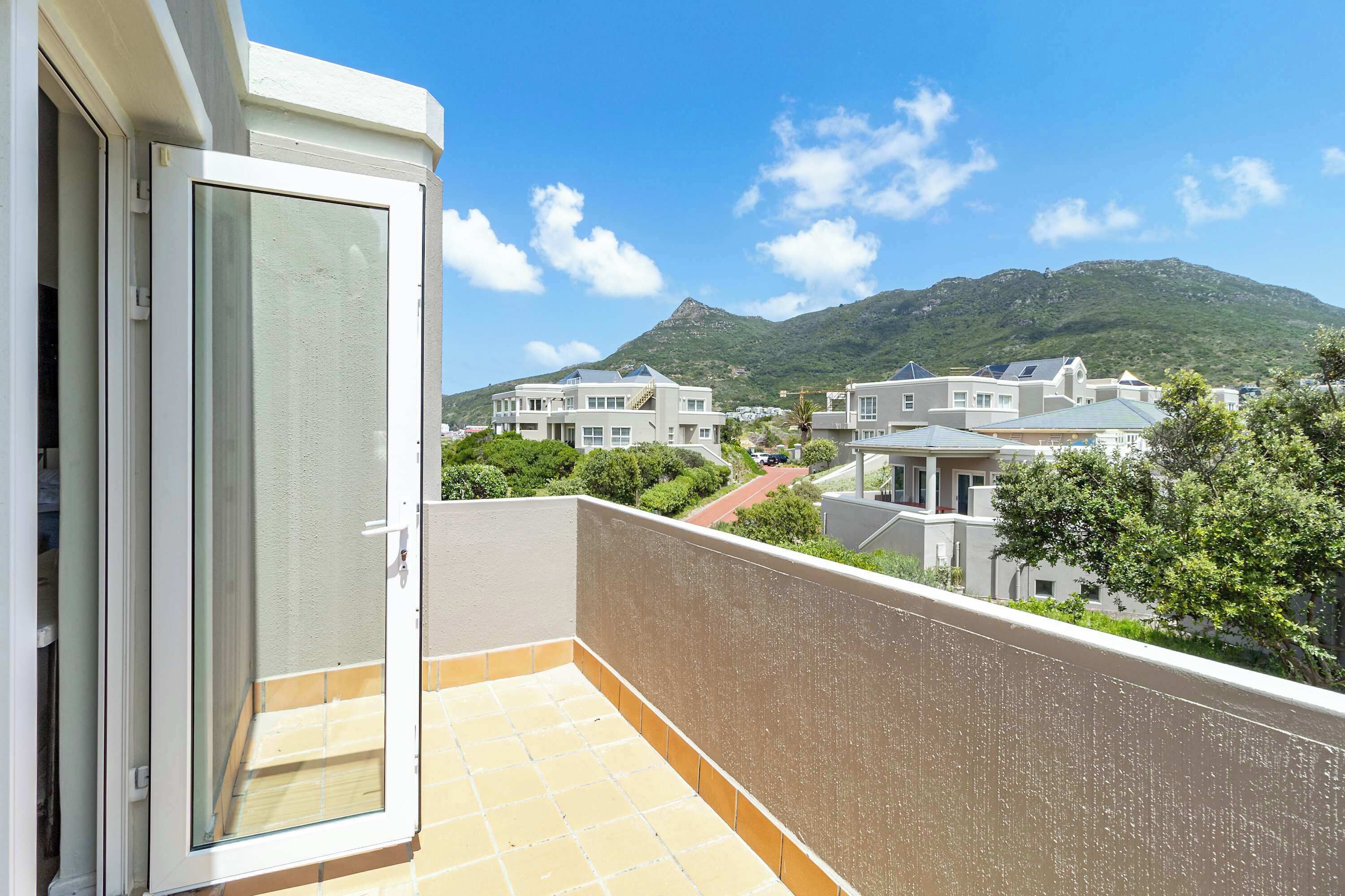 A balcony with a view of a residential area and a mountain.