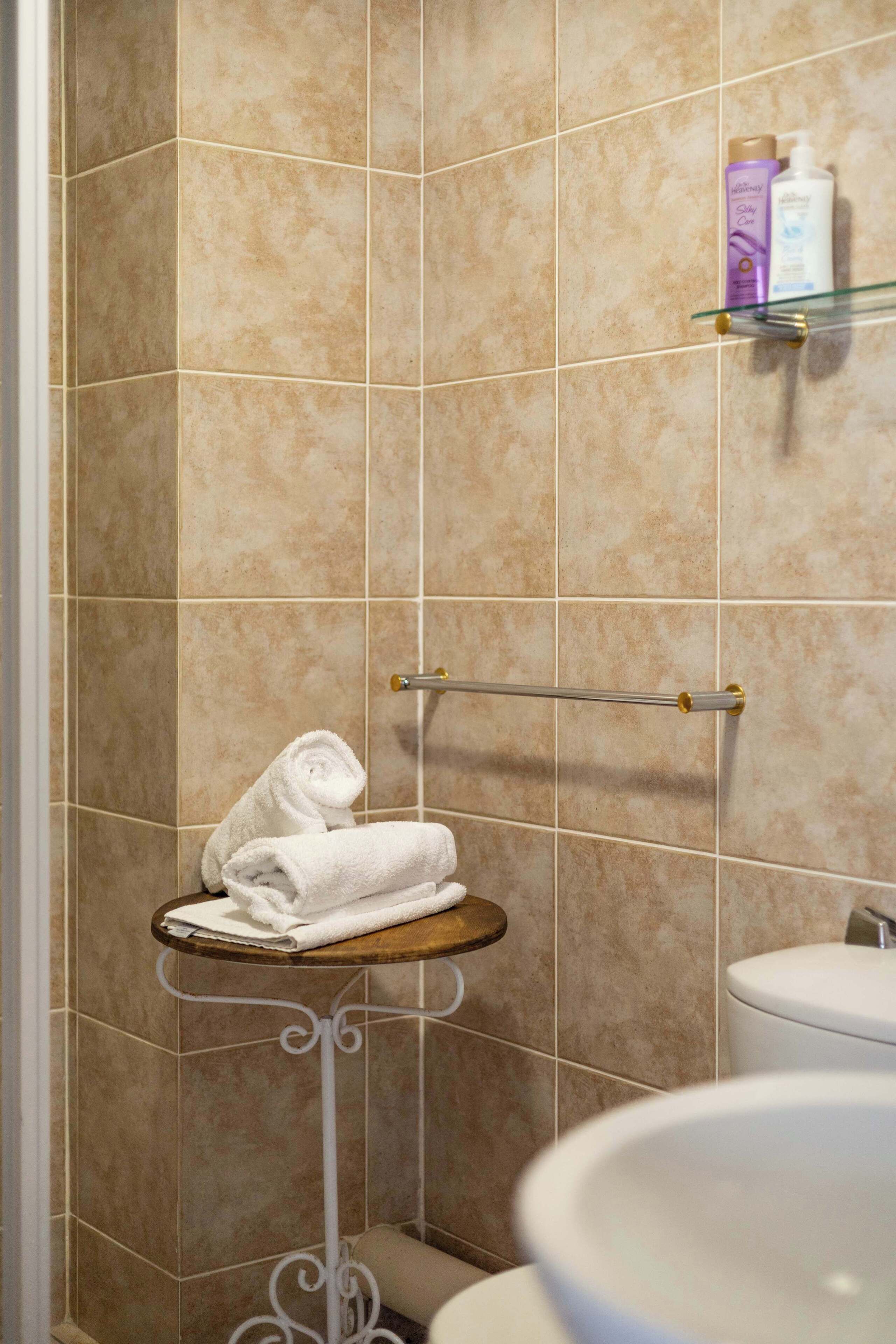 Een badkamer met behang van beige tegels, een witte wastafel, een handdoekhouder en toiletartikelen op een plank.