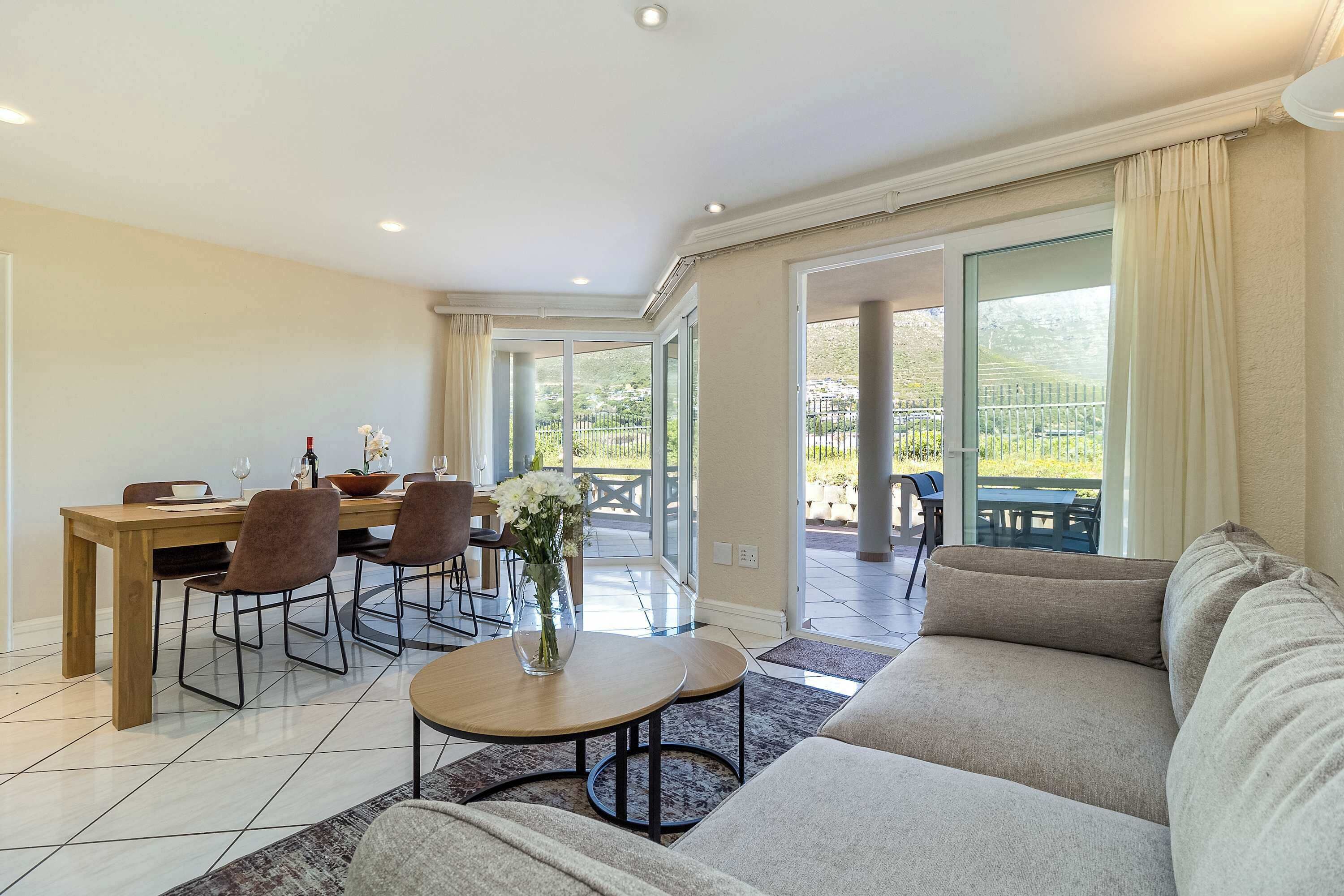 Ein modernes Wohnzimmer mit einer Couch, einem Esstisch mit Stühlen und einem Balkon mit Blick.