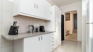 Een moderne keuken met witte kastjes, een granieten aanrechtblad en een ingebouwde koffiezetapparaat.