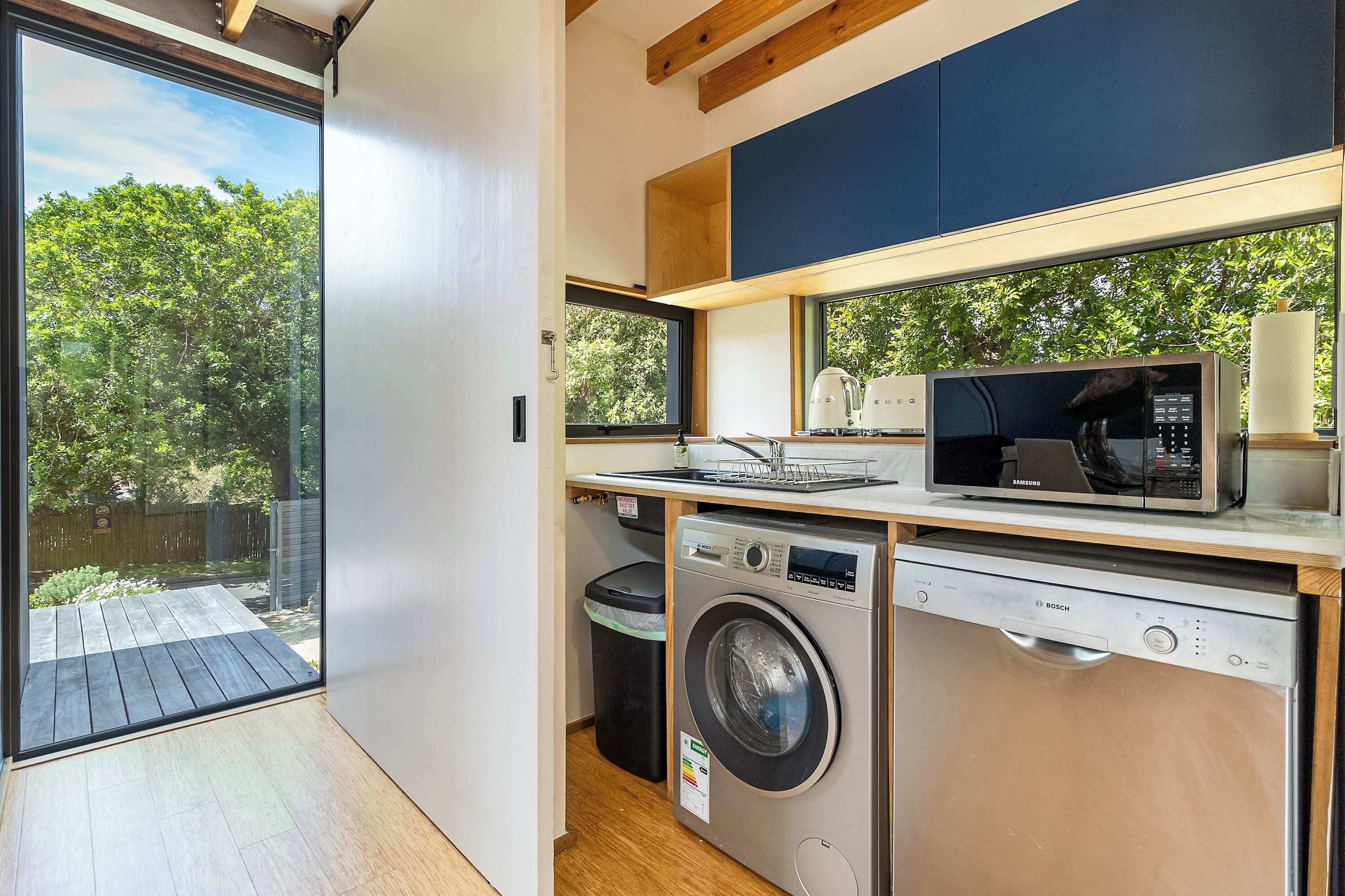 A compact kitchen with a washing machine, microwave, and sink.