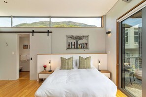 A modern bedroom with a large bed, a view of a mountain, and a sliding door to a balcony. - Luxury Eco Haven With Garden Cottage - Hout Bay (Cape Town)