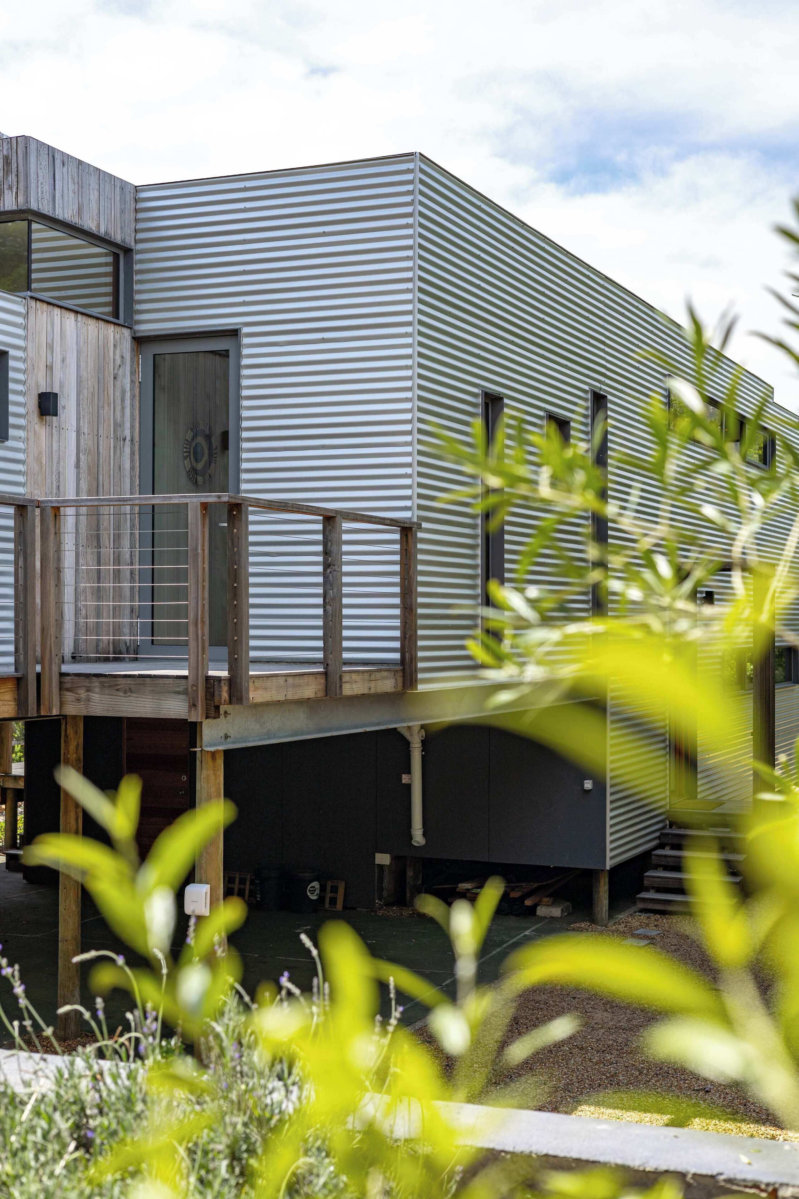 A modern building with a flat roof, a wooden deck, and a metal exterior.