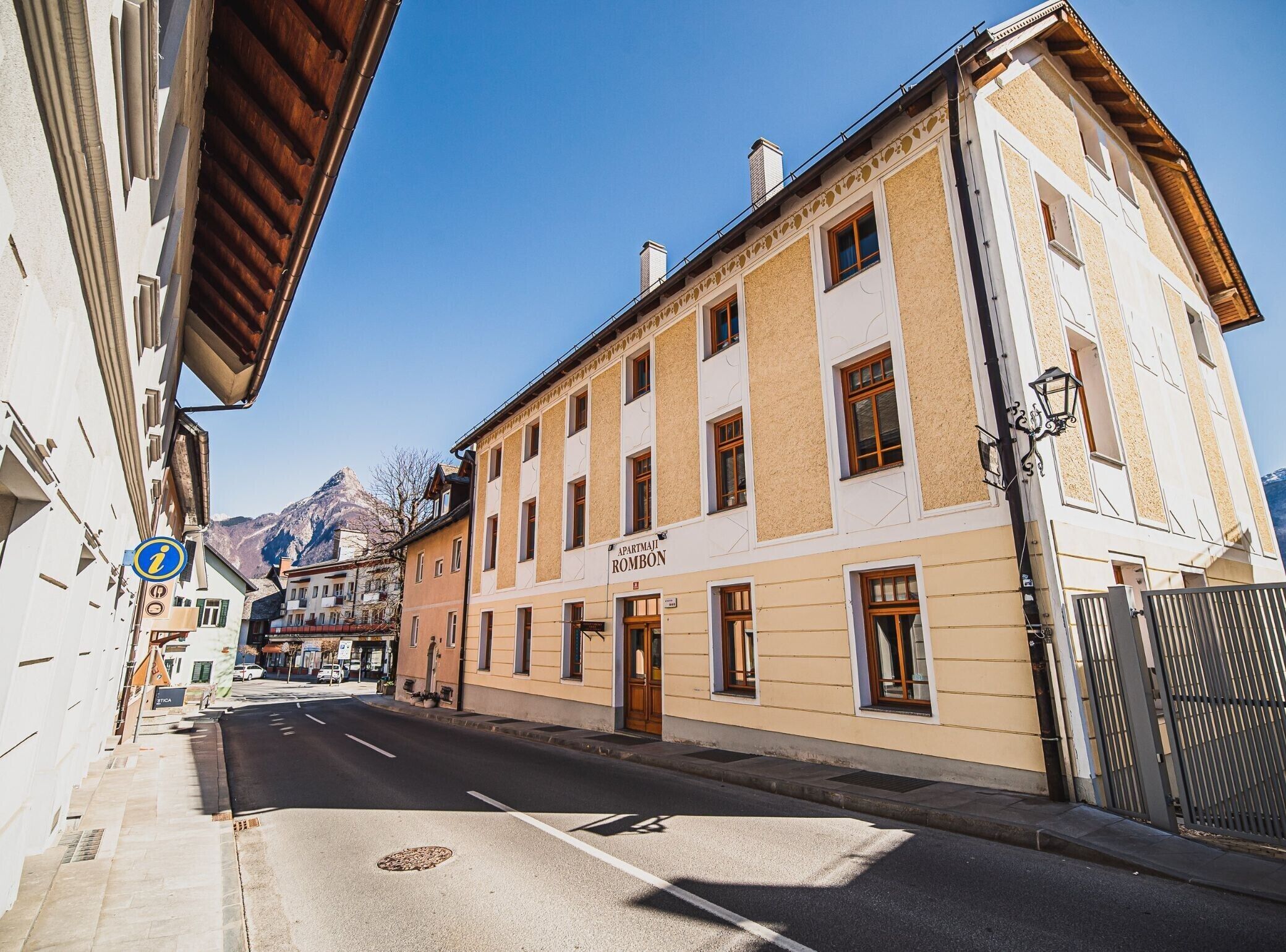 Une vue de rue d’un immeuble portant l’inscription « APARTEMENT ROMBON », qui présente un style architectural traditionnel avec de nombreuses fenêtres et une entrée bien visible.