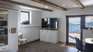 Eine moderne Küche mit weißen Schränken, einer Holzbalkendecke und einem großen Fenster mit Blick auf eine schöne Landschaft.