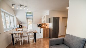 Una cocina moderna con comedor, un sofá gris y suelo de madera.
