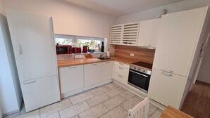A modern kitchen with white cabinets, a wooden countertop, a built-in oven, and a window overlooking greenery. - Idyllic and Charming Apartments with Terrace - Standard Two Bedroom Apartment with terrace (Preddvor)