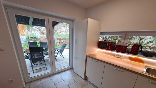 A modern kitchen with a sliding glass door leading to an outdoor seating area. - Idyllic and Charming Apartments with Terrace - Standard Two Bedroom Apartment with terrace (Preddvor)