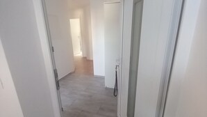 A hallway with a tiled floor, white walls, and a door with a frosted glass panel. - Idyllic and Charming Apartments with Terrace - Standard Two Bedroom Apartment with terrace (Preddvor)