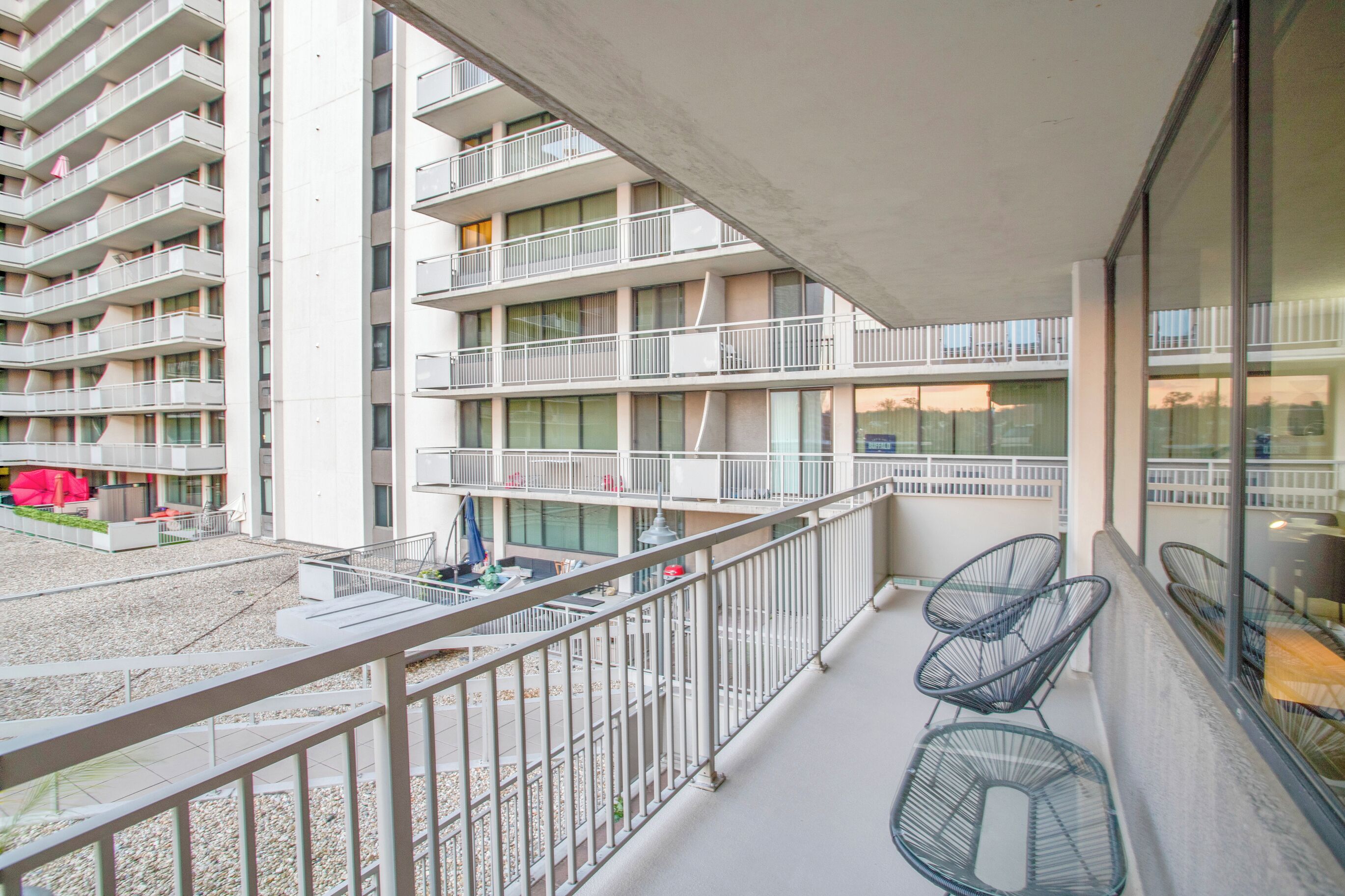 A multi-story building with balconies, outdoor seating, and a view of the surrounding area.
