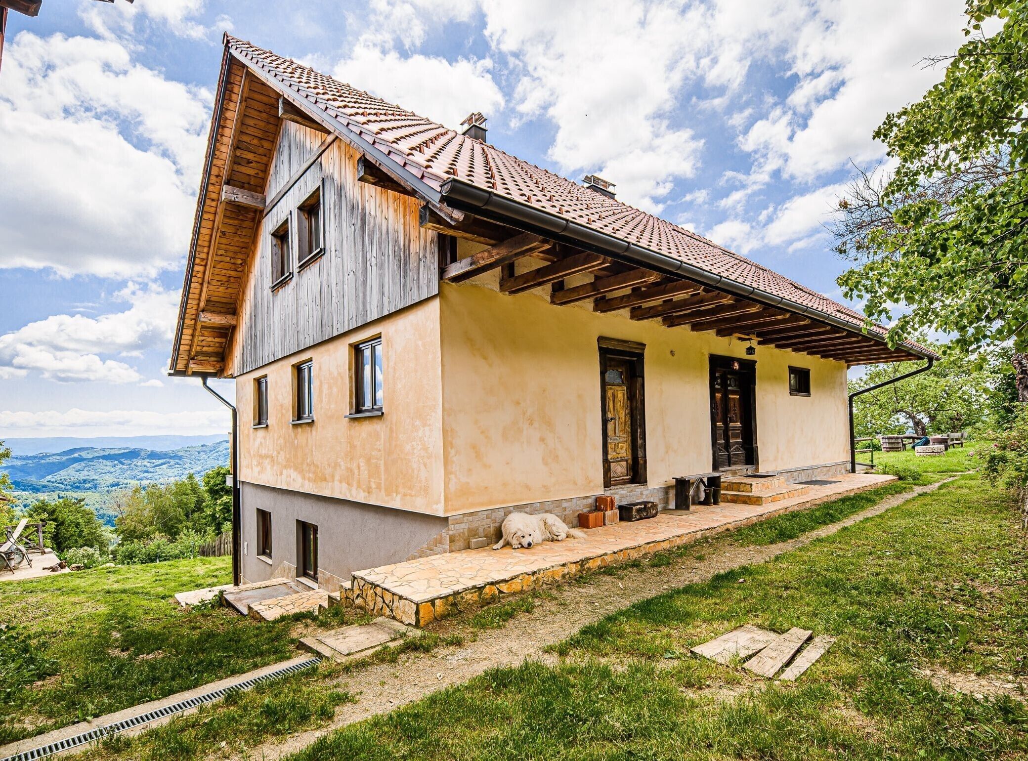 A two-story house with a sloped roof, a stone foundation, and a wooden exterior.