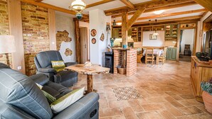 A cozy living room with a fireplace, leather sofa, and a rustic wooden ceiling. - Hidden Authentic Haven Apartments - Two Bedroom Apartment with Balcony (Sevnica)