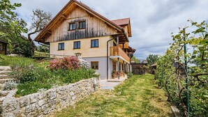 A traditional wooden house with a stone wall and a grassy yard. - Hidden Authentic Haven Apartments - Two Bedroom Apartment with Balcony (Sevnica)