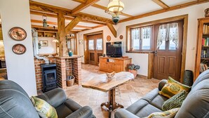 A cozy living room with a fireplace, leather sofas, a TV, and wooden beams. - Hidden Authentic Haven Apartments - Two Bedroom Apartment with Balcony (Sevnica)