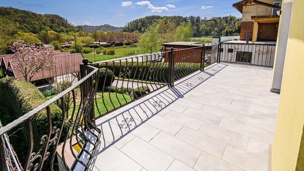 Un balcon donnant sur un paysage verdoyant et sur des collines lointaines.