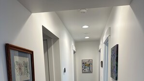 Un couloir aux murs blancs, au plancher en bois et aux œuvres d’art encadrées.