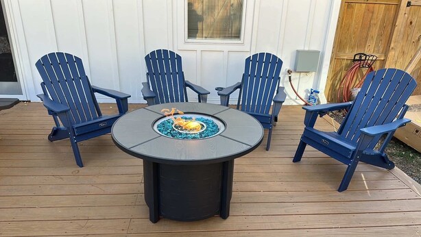 Une terrasse avec une table ronde et quatre chaises Adirondack.
