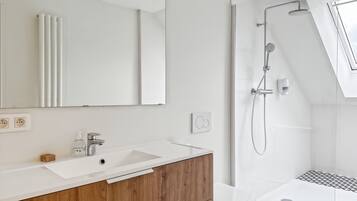 Une salle de bain moderne avec un meuble-lavabo blanc, un meuble en bois et une cabine de douche en verre.