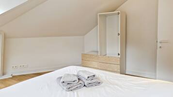 Une chambre avec un grand lit, un plancher en bois, un plafond blanc et une porte.
