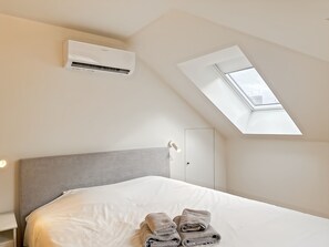 Ein Schlafzimmer mit Oberlicht, einem Bett und einer Klimaanlage.