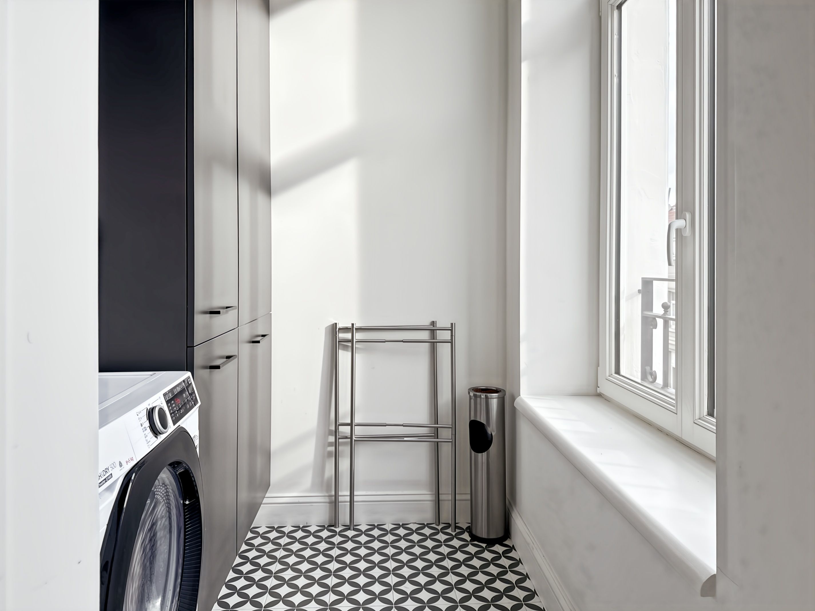 Une buanderie équipée d’un lave-linge, d’un étendoir et d’une poubelle.
