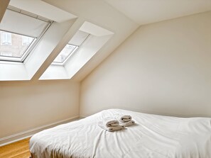 A bedroom with a skylight, a bed with white linens, and a wooden floor. - Charming Ixelles Apartment Retreat in the Heart of Brussels (Brussels)