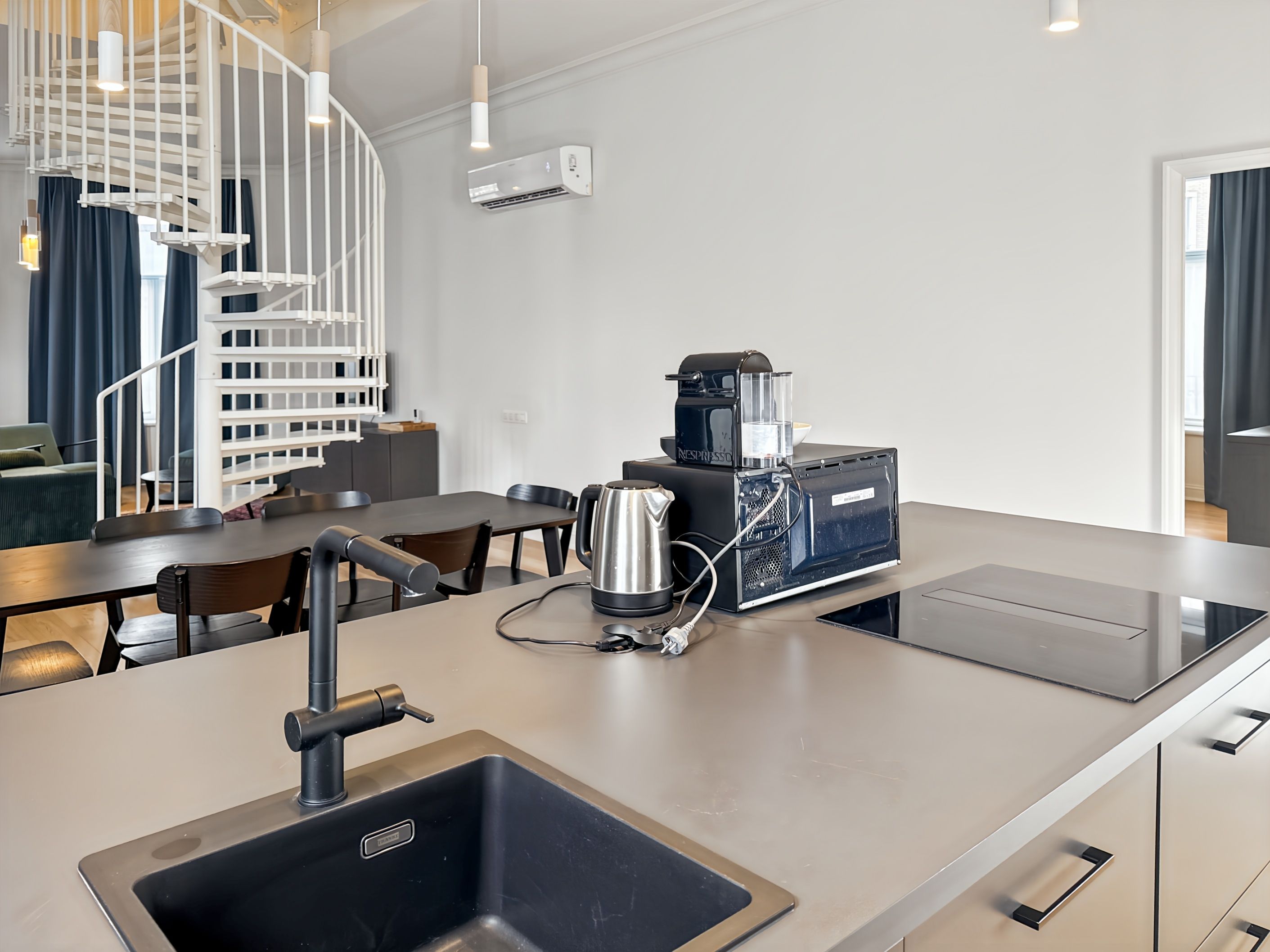 Une cuisine moderne équipée d’une machine à expresso intégrée, d’une bouilloire et d’un évier.