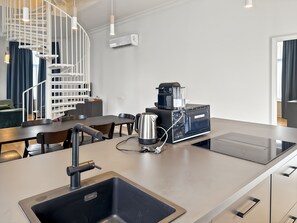 Una cucina moderna con macchina da caffè espresso integrata, bollitore e lavandino.