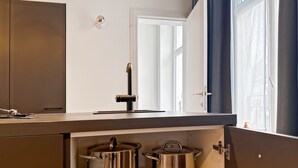 Eine Küche mit Einbauherd, zwei Edelstahl-Töpfen und einem Fenster mit Vorhängen.