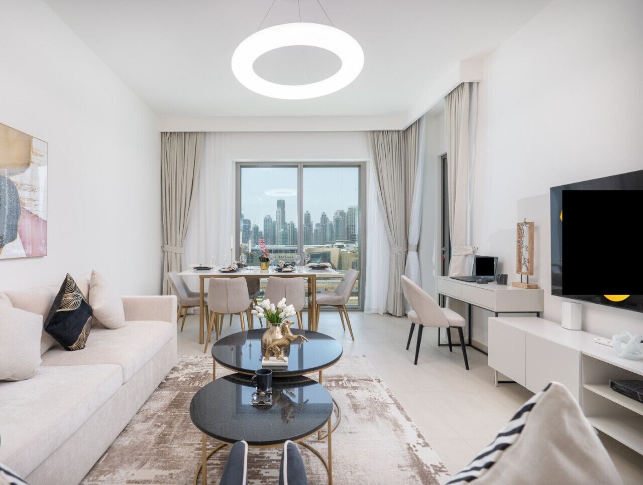 A modern living room with a sofa, coffee table, dining area, and a TV.