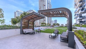 Une terrasse extérieure avec des sièges, une pergola et une vue sur les immeubles de grande hauteur.