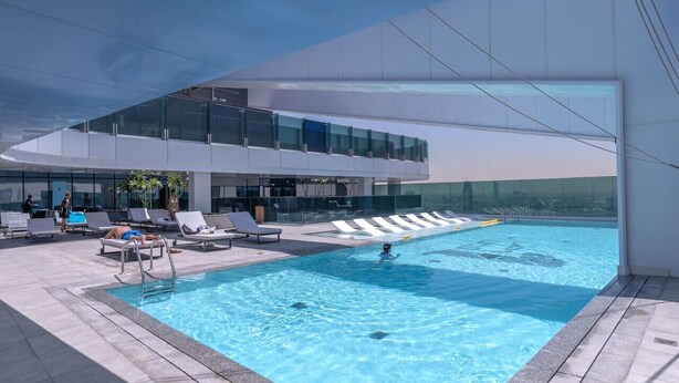 Une piscine intérieure moderne, avec une eau d’un bleu limpide, entourée de chaises longues et dotée d’une balustrade en verre.
