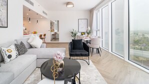 Un vaste espace de vie comprenant un canapé moderne, une table à manger avec des chaises et une grande fenêtre donnant sur la ville.