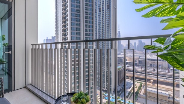 Varanda com vista para edifícios altos e uma piscina.