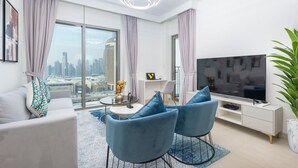 Uma sala de estar moderna com vista para a cidade, uma TV de tela plana e uma área de jantar com cadeiras azuis.