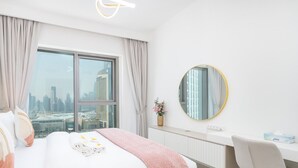 Quarto de hotel moderno com uma cama grande, uma mesa e vista para o horizonte da cidade.
