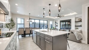 Una cucina moderna con una grande isola, elettrodomestici in acciaio inossidabile e lampade a sospensione.