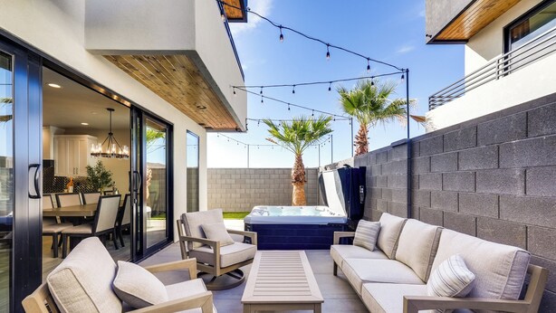 Patio esterno con divano, sedie, tavolo e vasca idromassaggio.