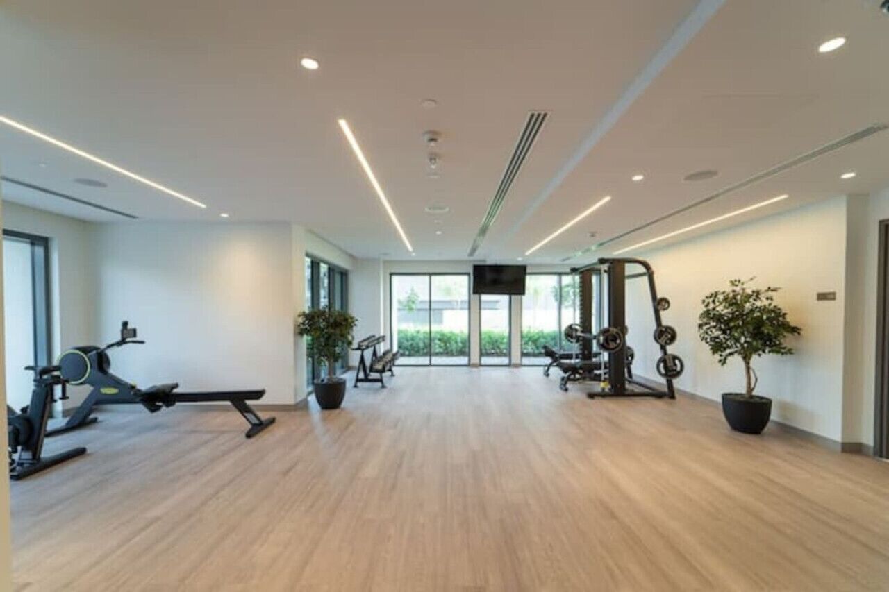 Een moderne sportschool met trainingsapparatuur, grote ramen en potplanten.