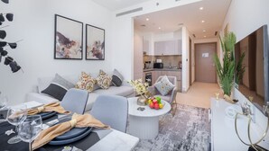 Ein modernes Wohnzimmer mit Sofa, Esstisch und einer Küche im Hintergrund.