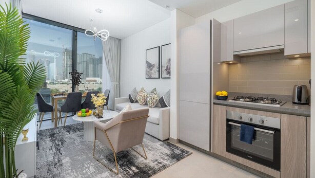 Eine moderne Küche mit Backofen, eine Essecke mit weißem Tisch und Stühlen sowie ein großes Fenster mit Blick auf die Stadt.