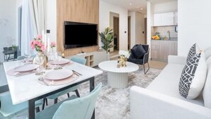 Una sala de estar moderna con comedor, televisor de pantalla plana y cocina al fondo.