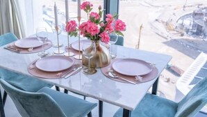 Una mesa de comedor dispuesta con platos rosas, un jarrón de flores rosas y velas.
