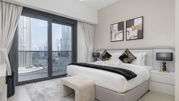 Un dormitorio moderno con una cama grande, vistas de la ciudad y un balcón.