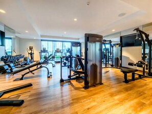 A modern gym with various exercise equipment, large windows, and a wooden floor. - Vogue, Act Two near Burj Khalifa and Dubai Mall (Dubai)